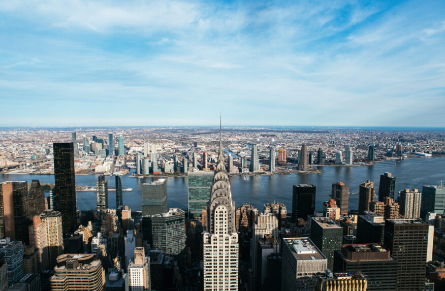 Breathtaking drone view of modern skyscrapers near river in Manhattan district against cloudy blue in New York City with chrysler building